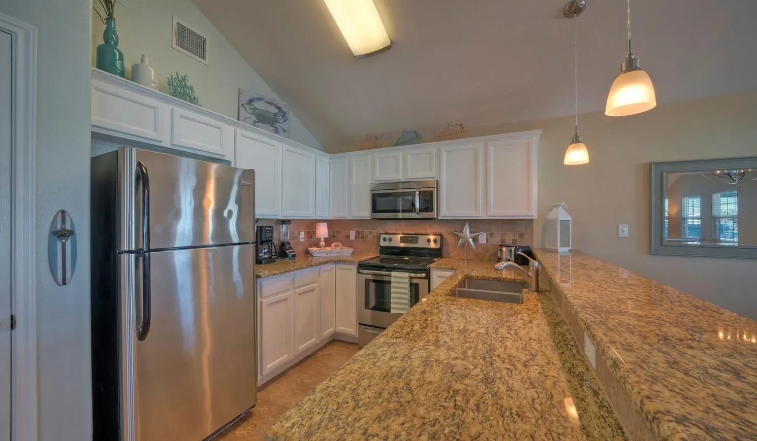 A spacious kitchen with white cabinetry, stainless steel appliances, and granite countertops.