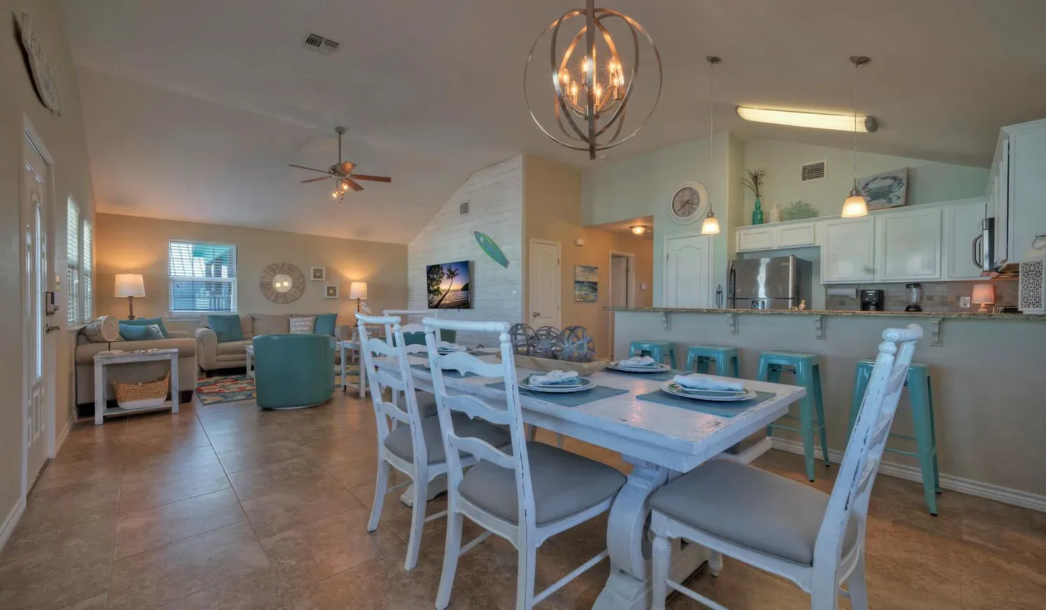 A dining area with a set table opens onto a living area and kitchen.