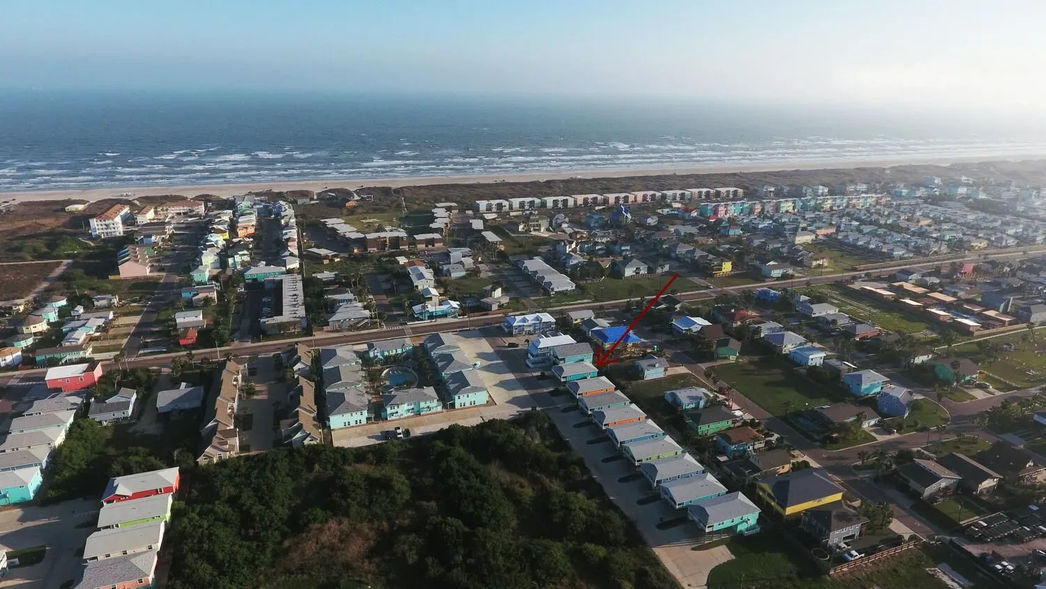 An aerial view of a coastal neighborhood with the ocean in the distance.
