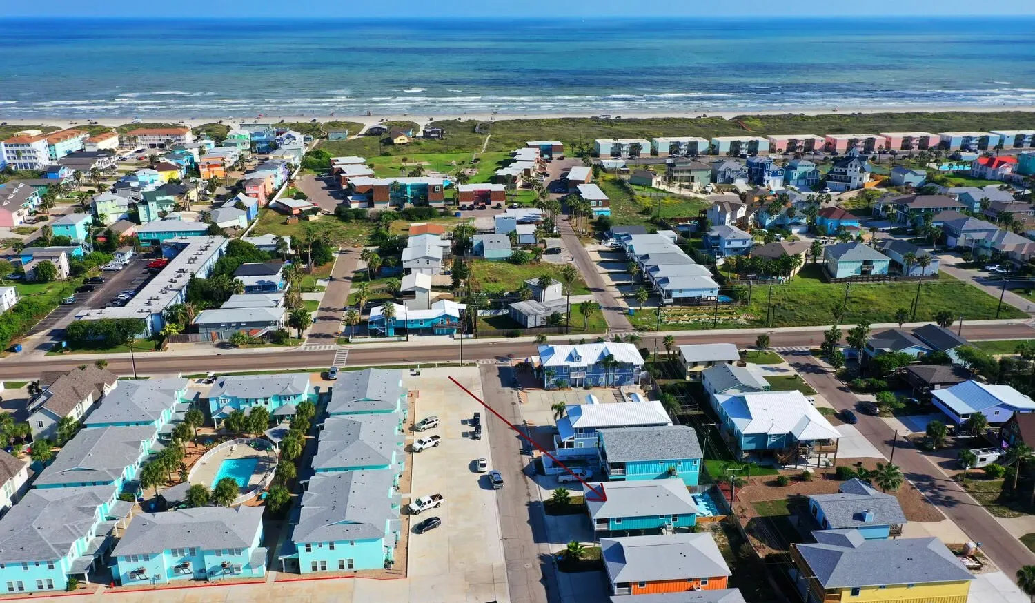 Aerial view of a coastal neighborhood with homes and the ocean beyond.