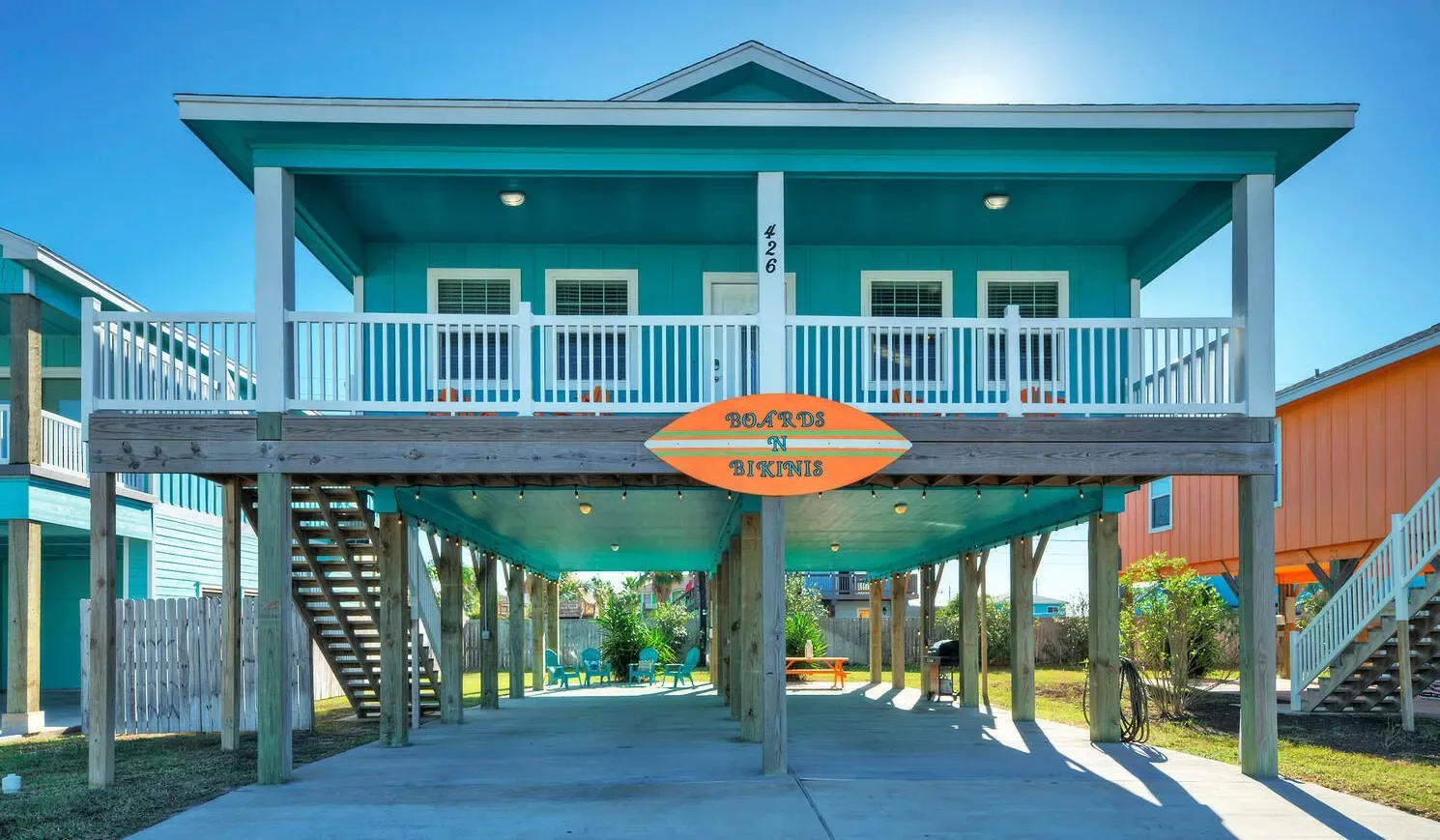 A raised coastal-style building with a covered upper balcony and open space below.