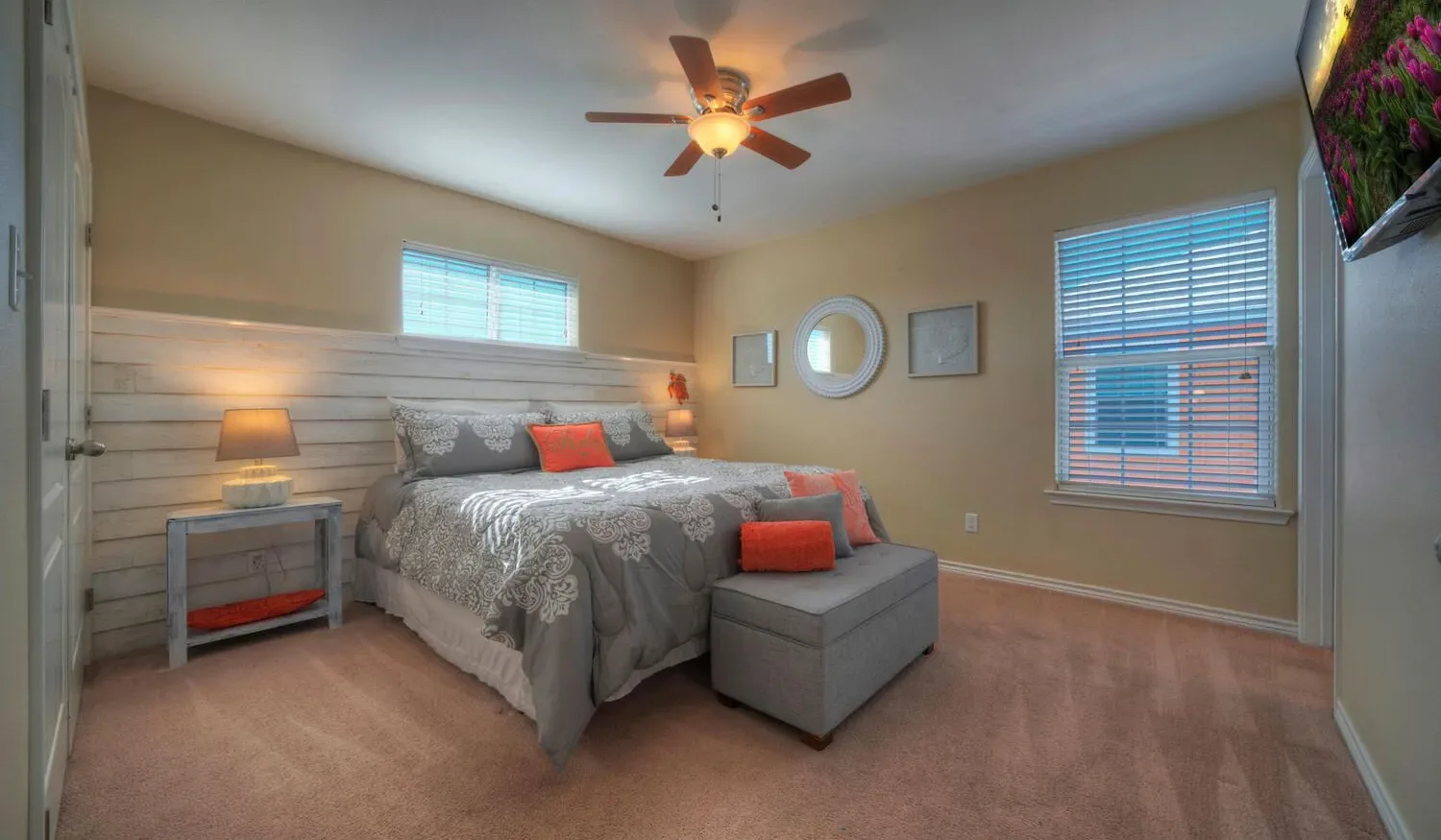 A bedroom with a bed, an upholstered bench, and windows with blinds.