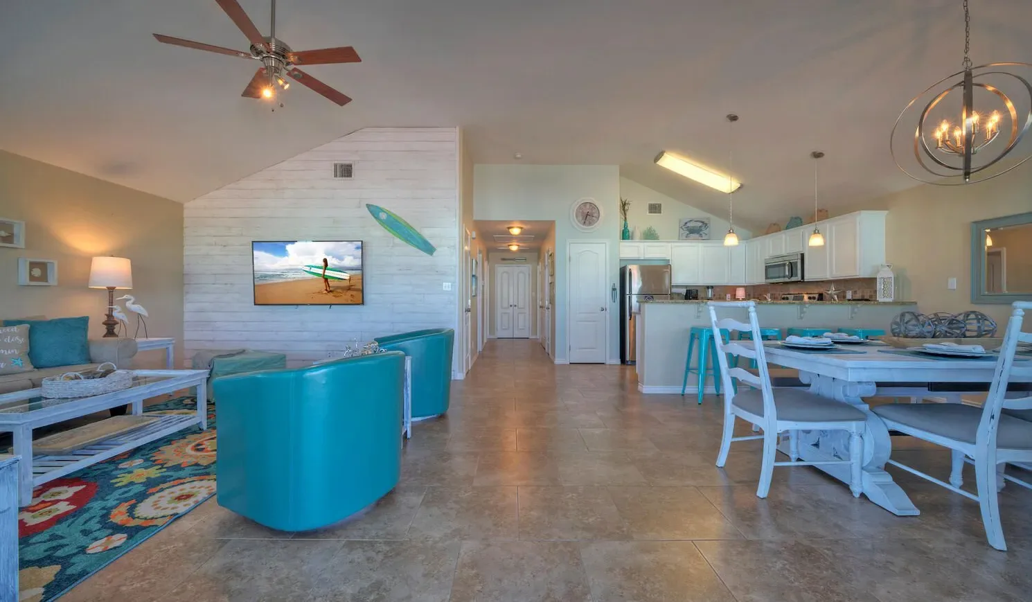 An open-plan living and dining area with turquoise seating and a dining table.
