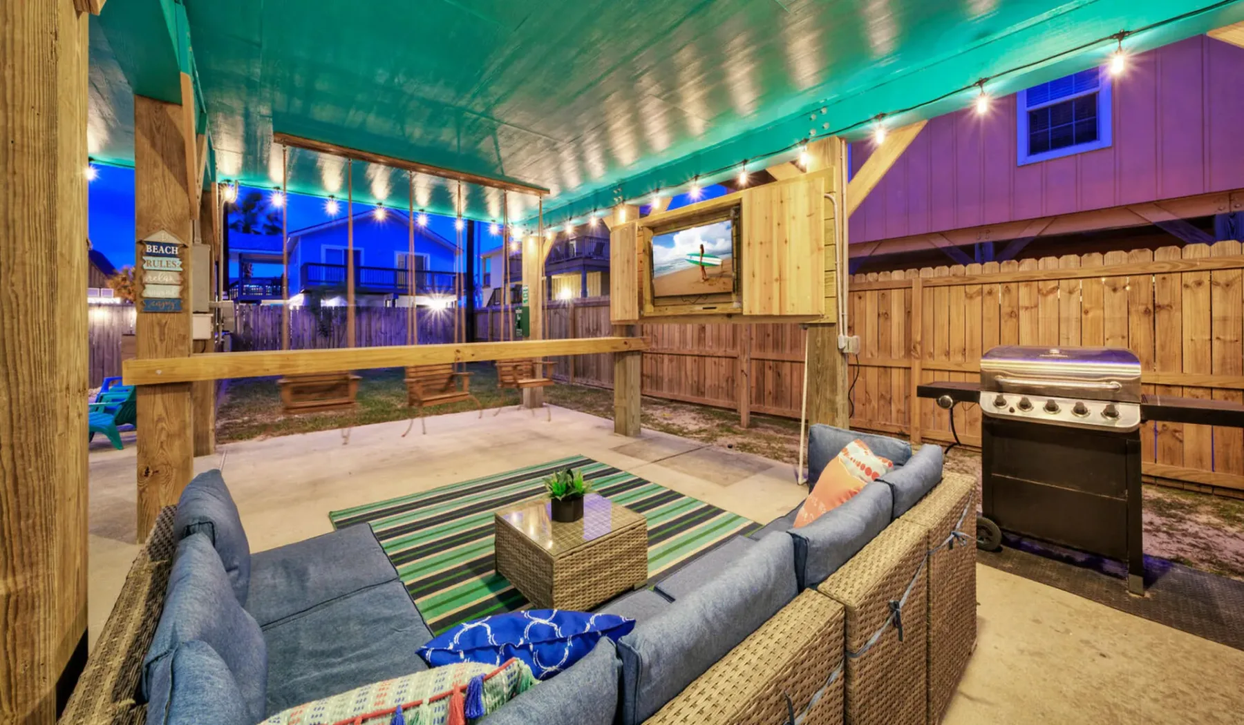 A covered outdoor seating area with a striped rug and barbecue grill.