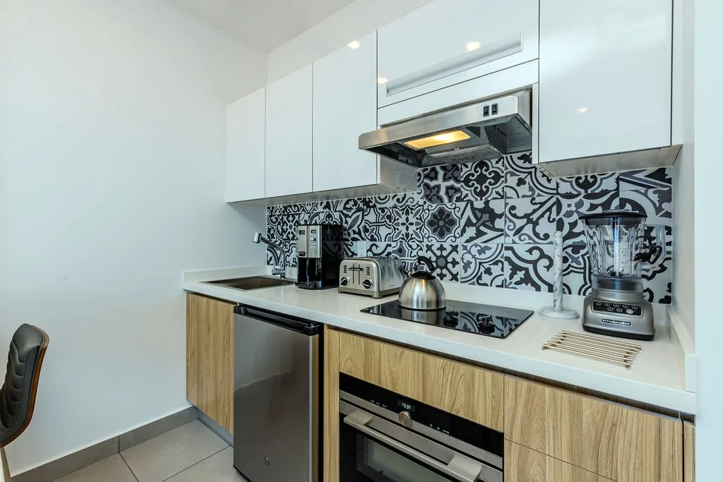 Your modern kitchenette features sleek cabinetry, stylish patterned tile backsplash, and everything you need—stove, microwave, toaster, coffee maker, and blender for easy meal prep.