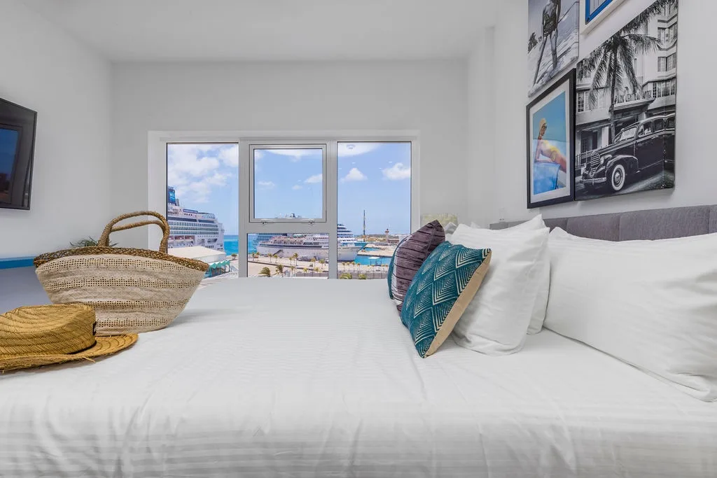 Drift off in a bright bedroom with plush bedding, coastal charm, and sweeping sea views that bring the harbor right to your window.