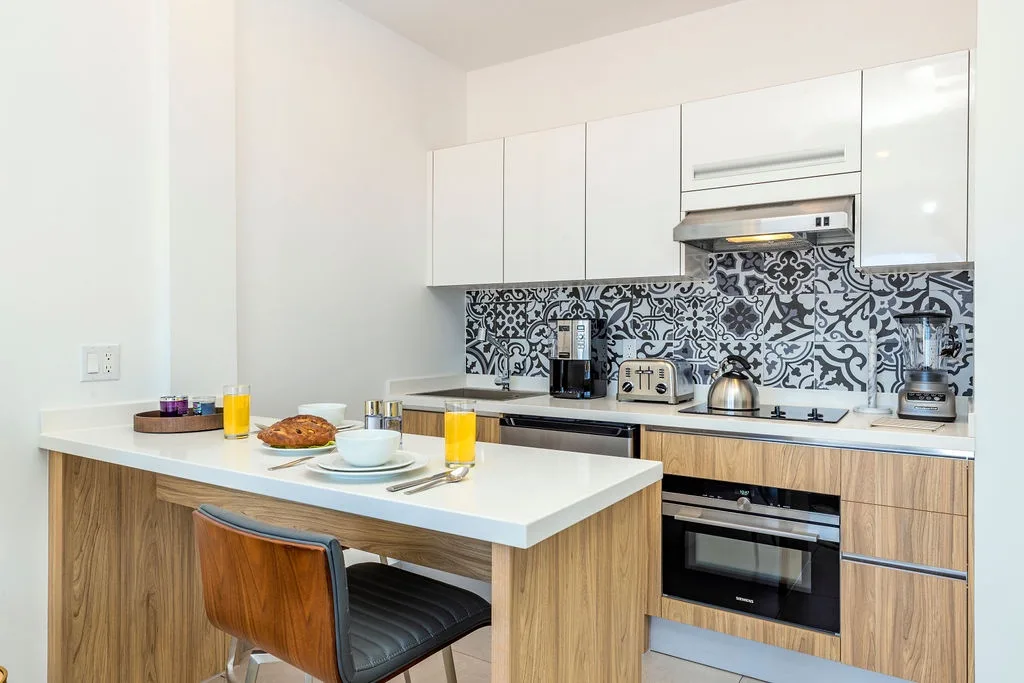 Your sleek, modern kitchen features stylish tile backsplash, stainless appliances, and a breakfast bar with fresh pastries and orange juice waiting for you.