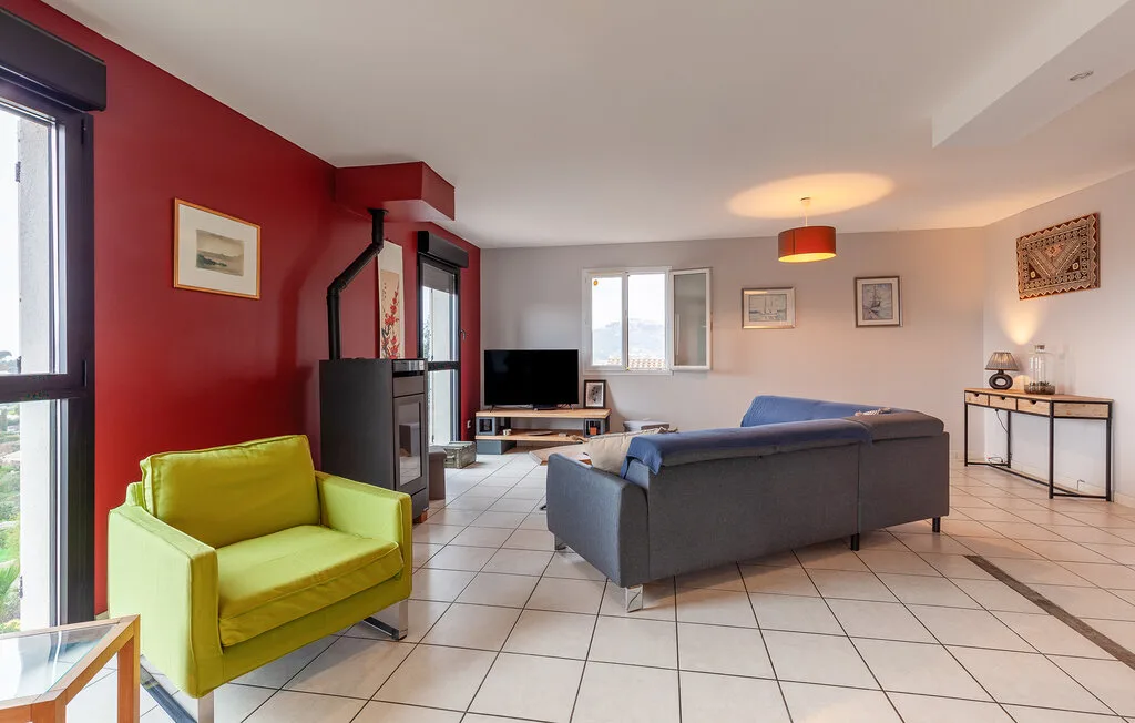A living room with seating, a television, and large windows.