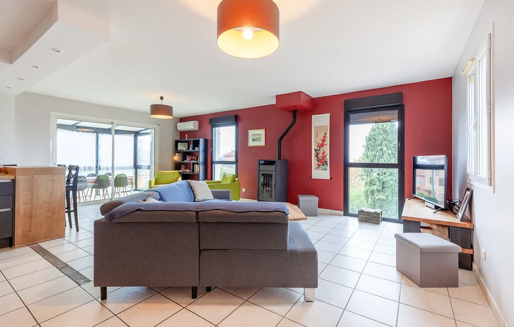 A bright living room with seating, a television, and large windows.