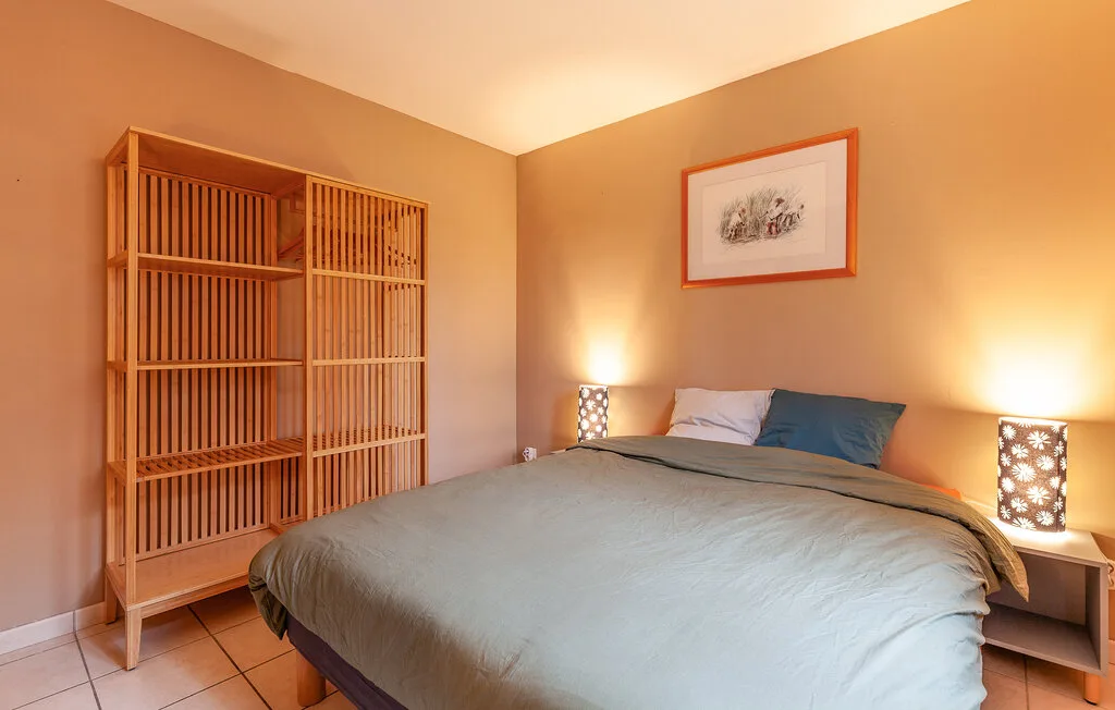 A bedroom with a neatly made bed and a tall wooden shelving unit.