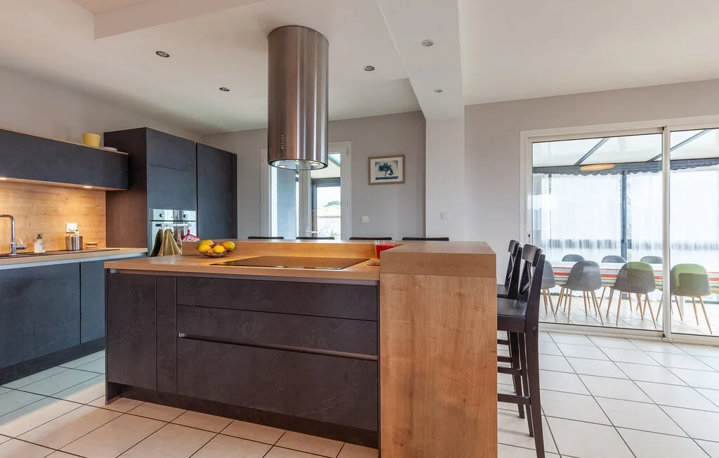 A modern kitchen with a central island opens onto a dining area.