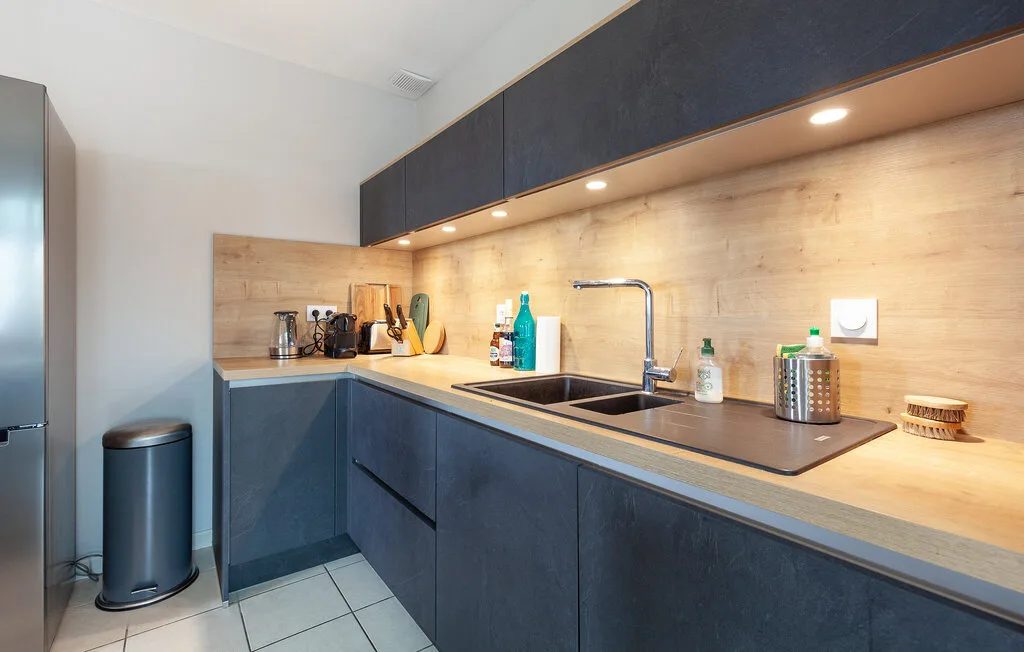 A modern kitchen with dark cabinets, a countertop, and a sink.