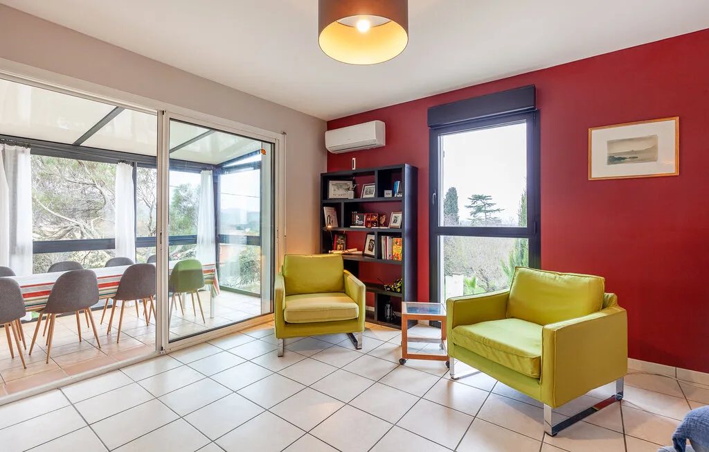 A bright living room with green seating, a bookshelf, and large glass doors.