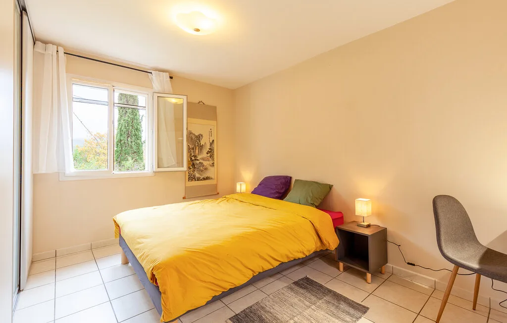 A bedroom with a bed, bedside table, and a window.