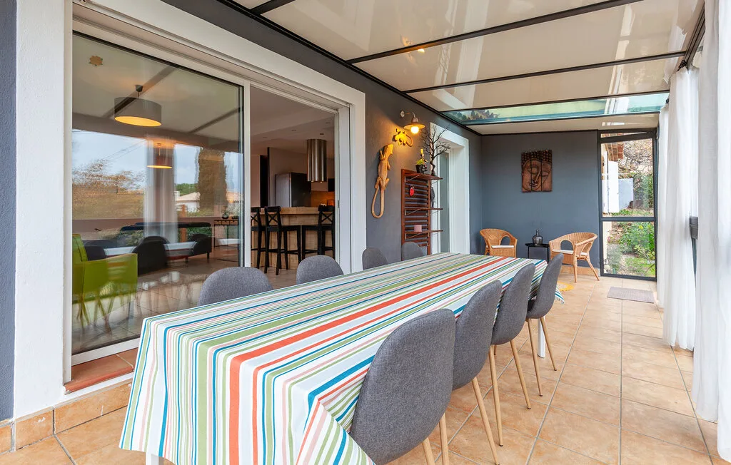 A covered dining patio with a long striped table and seating.