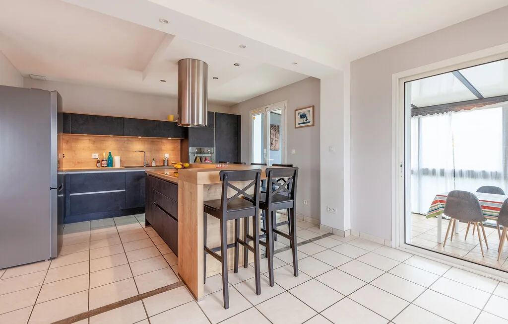 A modern kitchen with a wooden island and seating beside sliding glass doors.