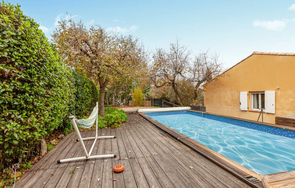 A swimming pool beside a wooden deck and garden.
