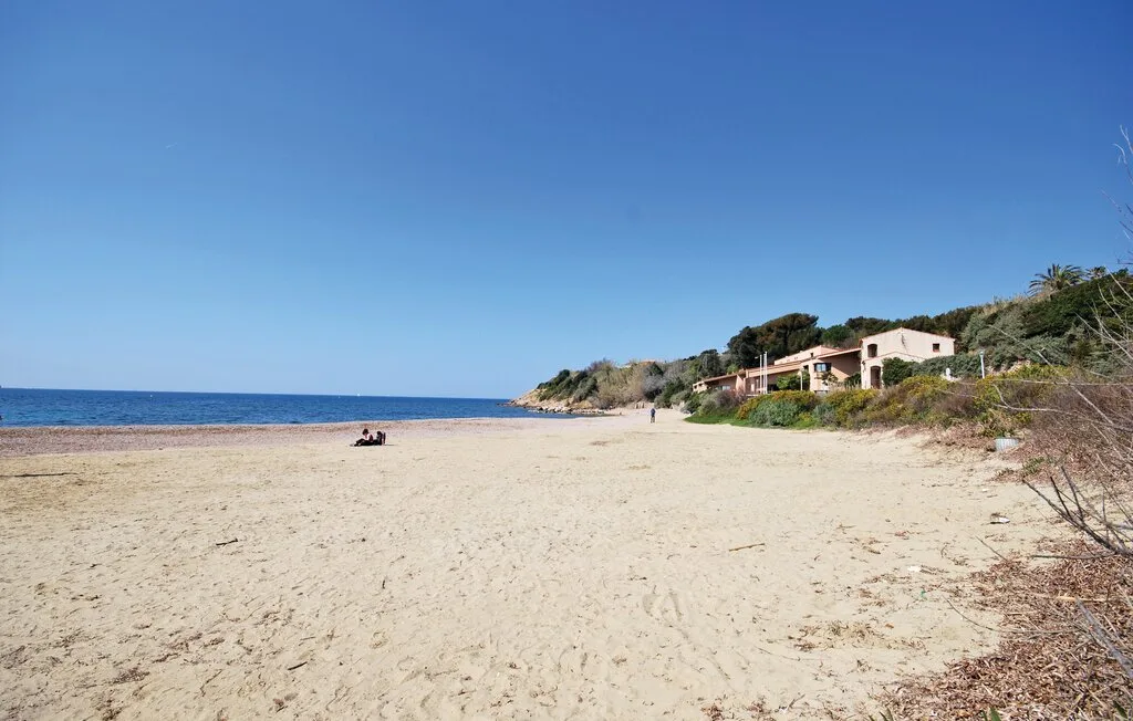 A sandy beach stretches beside the blue sea, with houses along the shore.