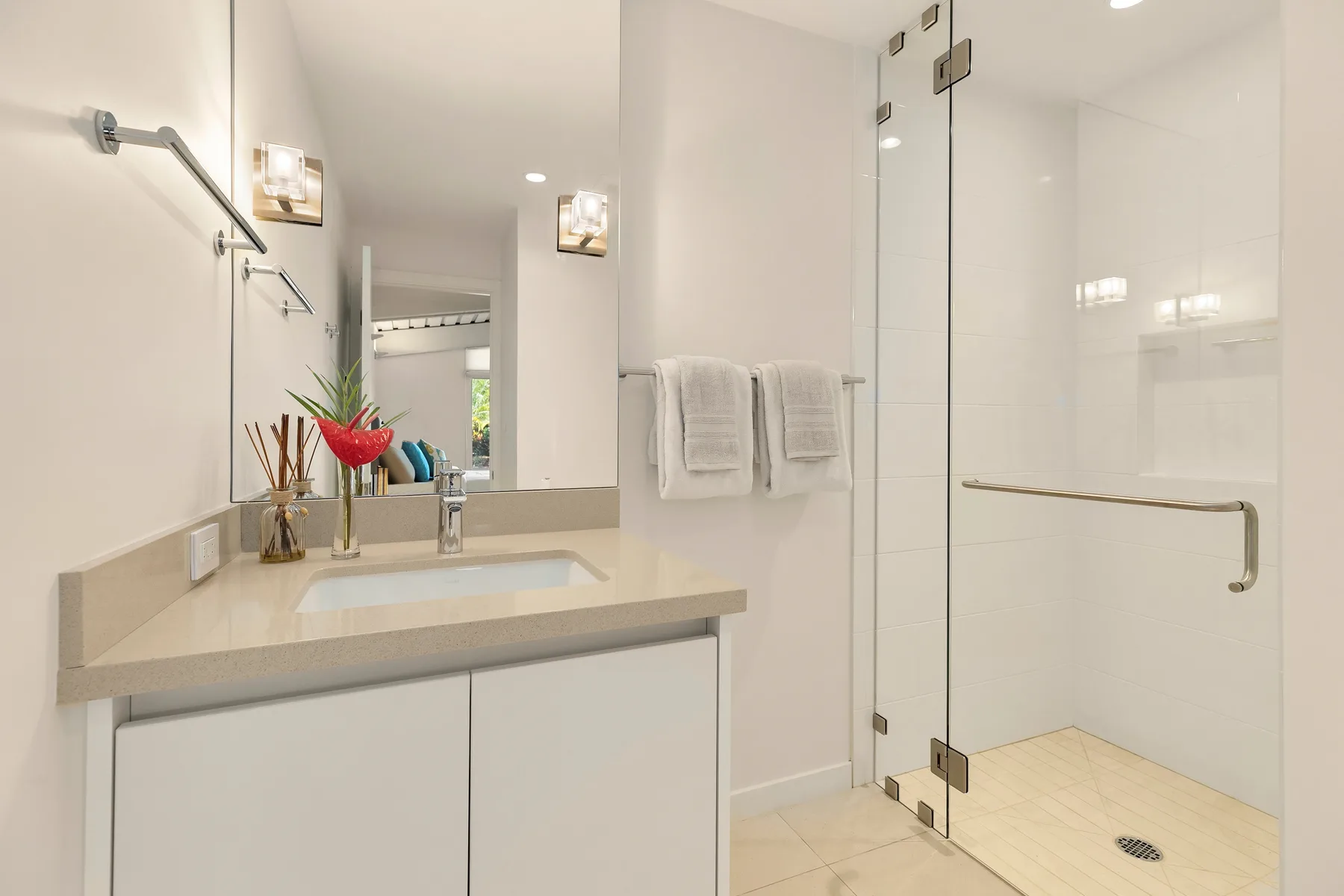 Un baño luminoso con tocador, espejo y ducha de vidrio.