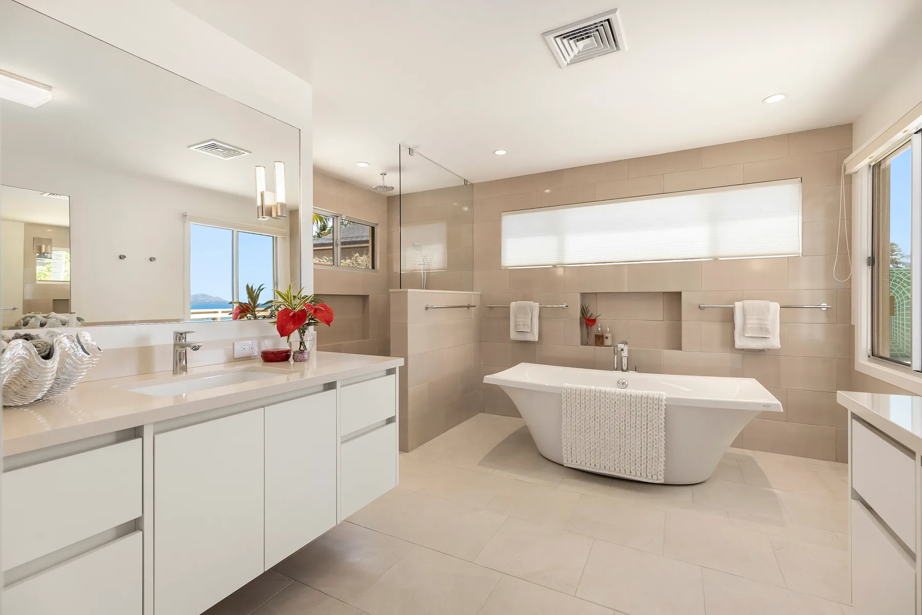 Un baño luminoso con una bañera exenta y un lavabo largo.