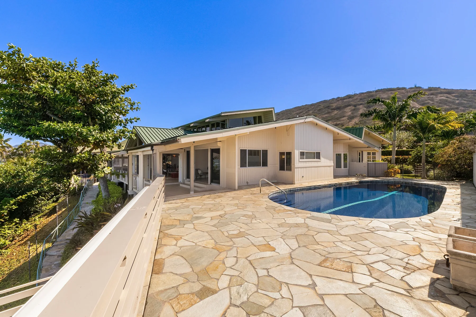 Una casa da a un patio de piedra con una piscina.