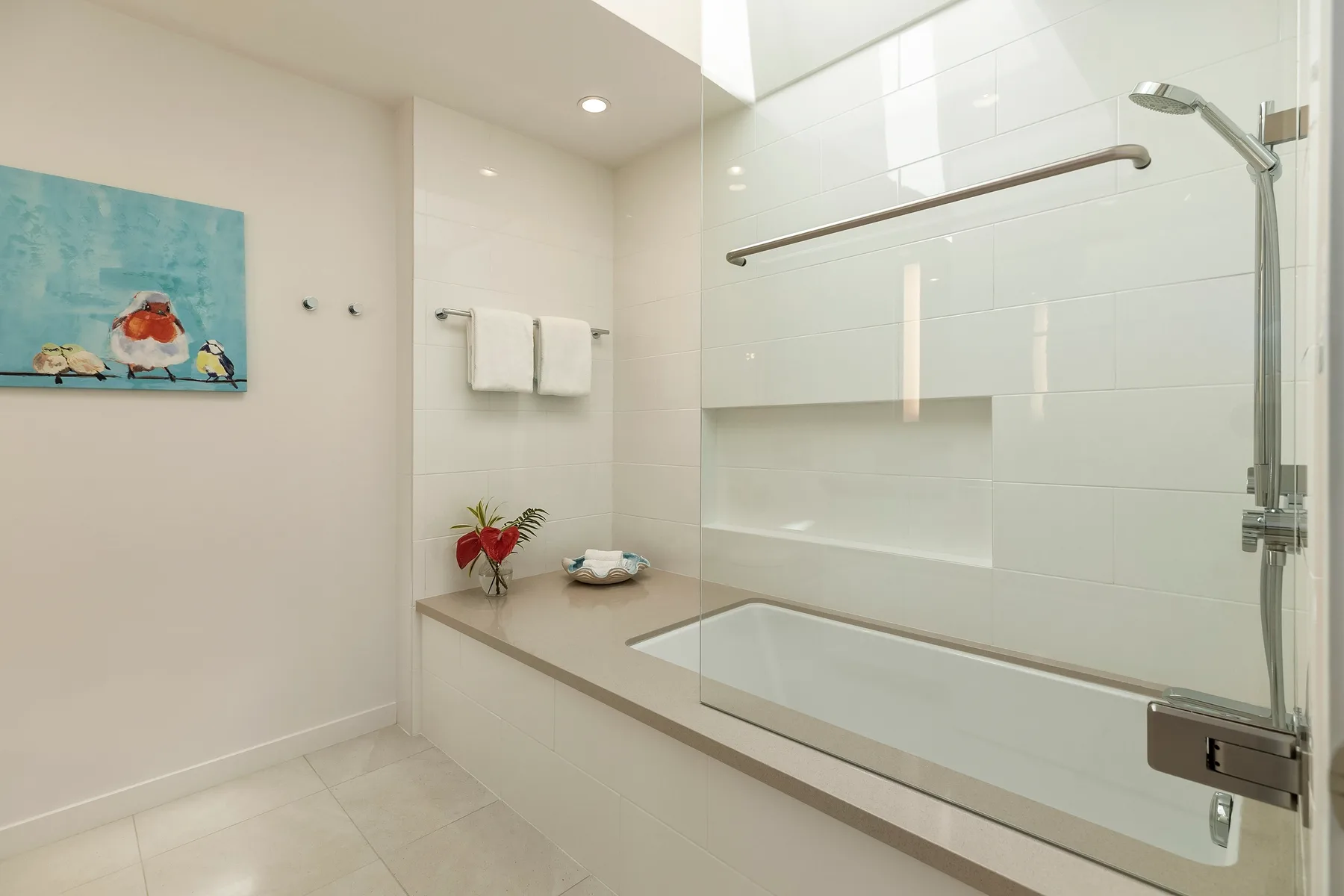 Un baño luminoso con bañera, mampara de vidrio y ducha de pared.