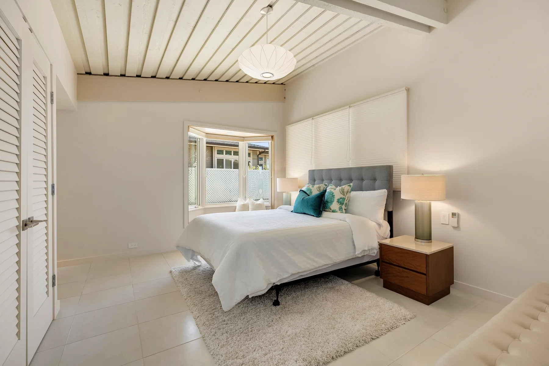 Un dormitorio luminoso con una cama tendida y lámparas de mesita.