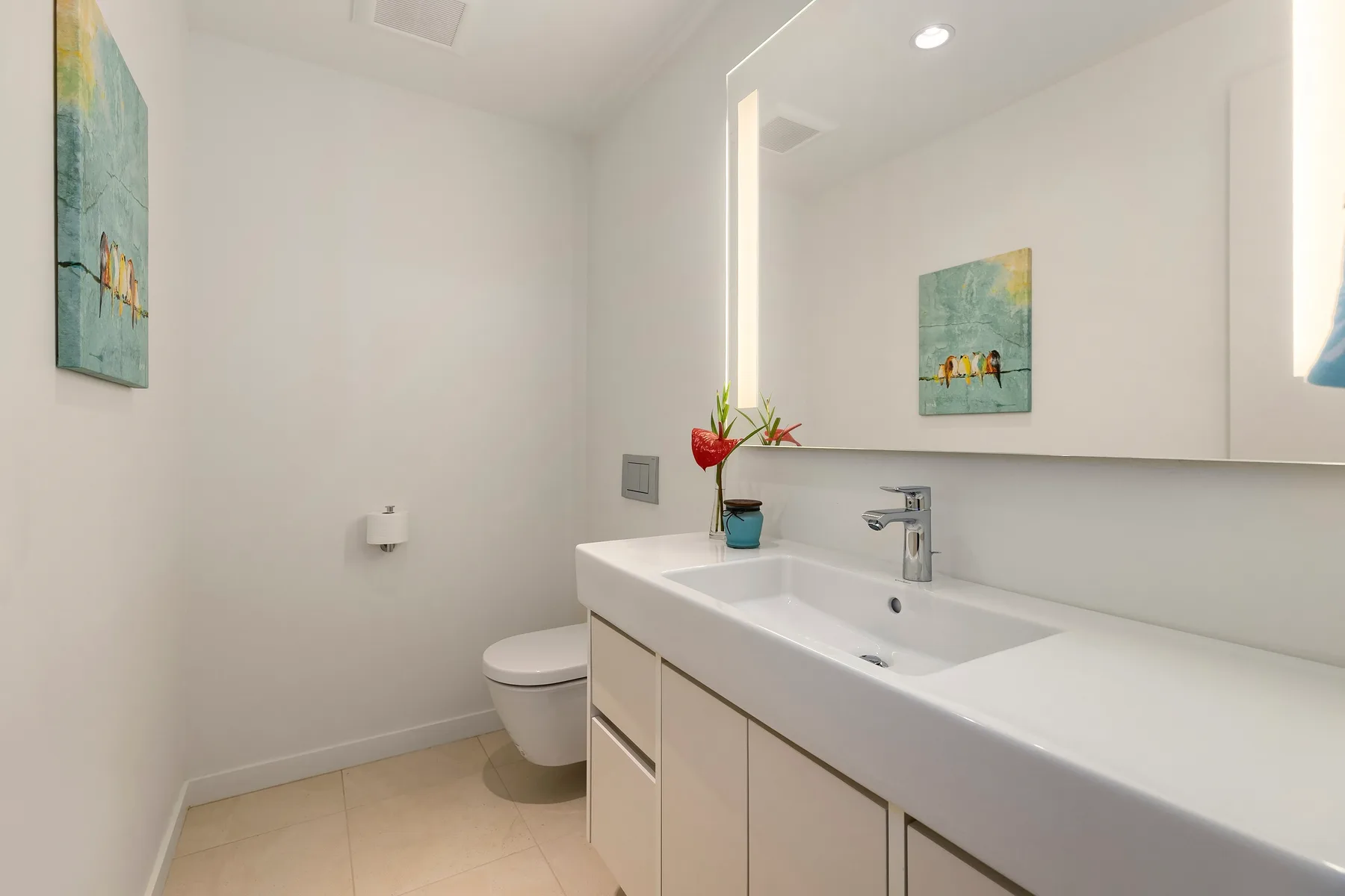 Un baño luminoso tiene un largo tocador con lavabo y un espejo grande.