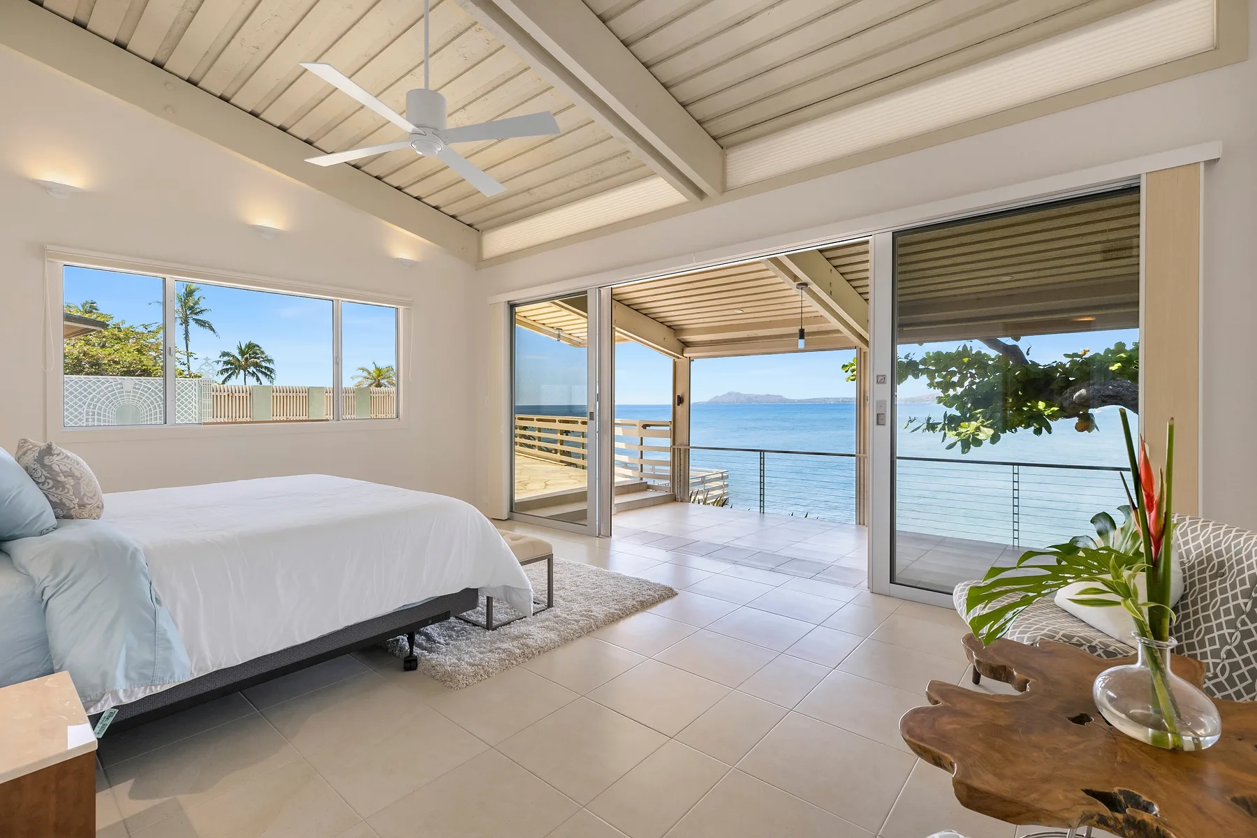 Un dormitorio luminoso da a un balcón cubierto con vistas al mar.