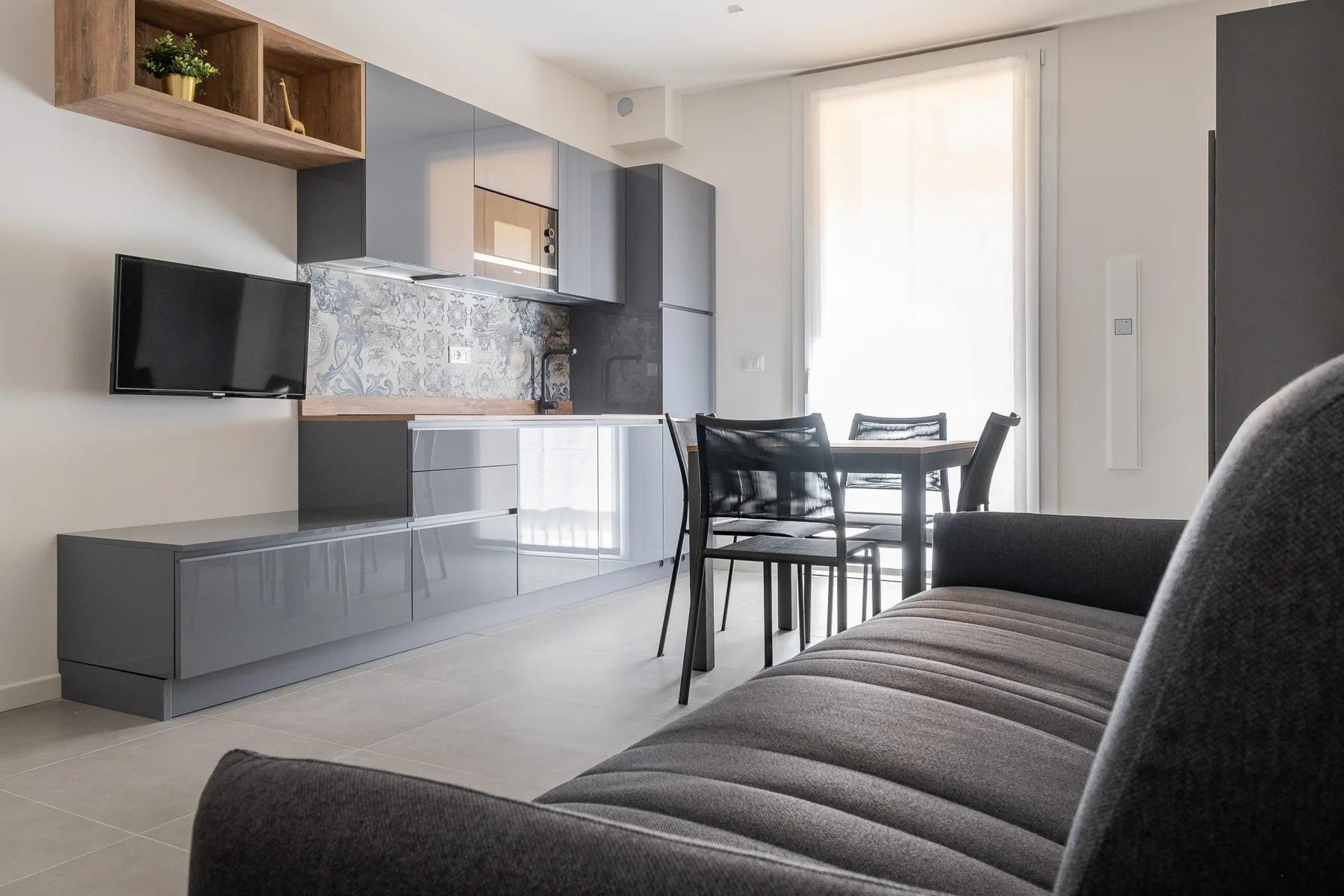 A modern kitchen and dining area with a sofa in the foreground.