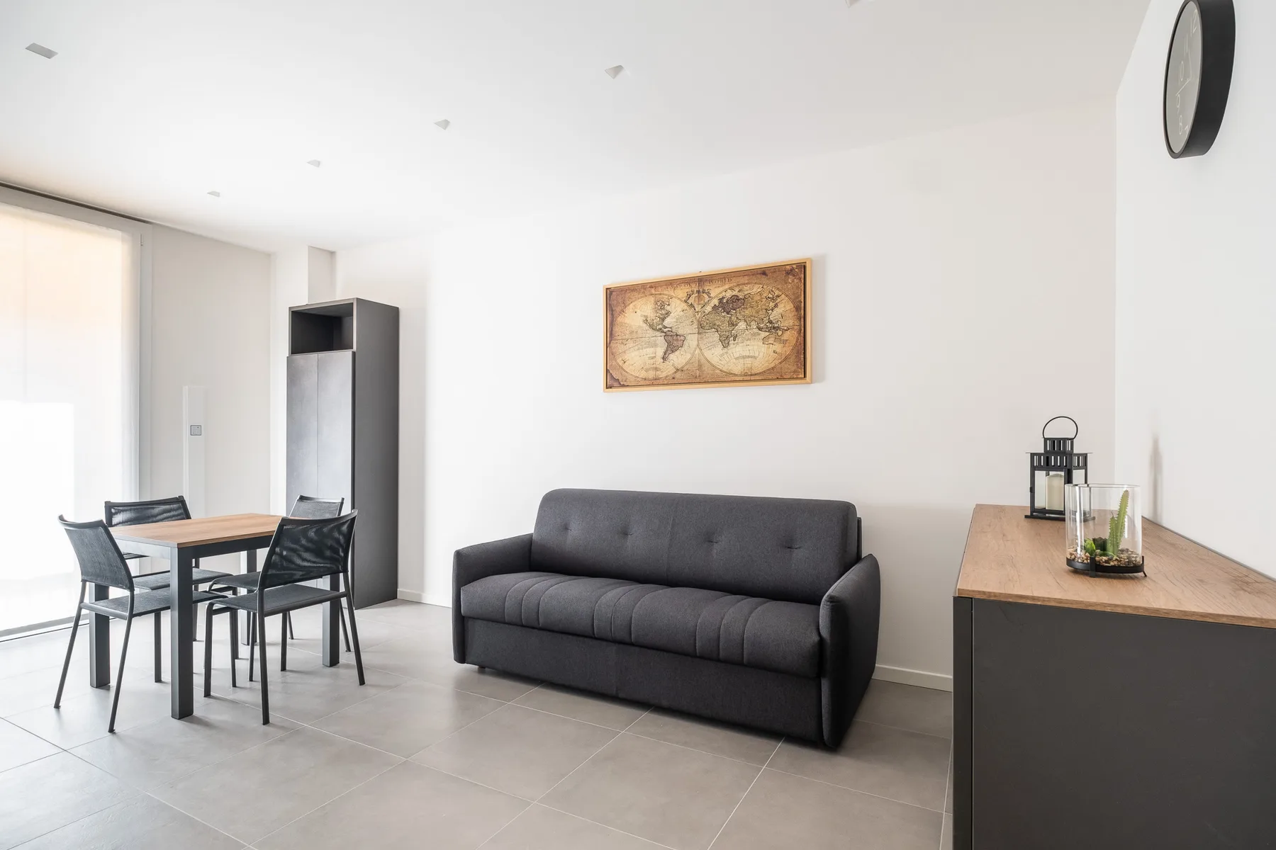 Una luminosa sala de estar y comedor con un sofá oscuro y una mesa de comedor.