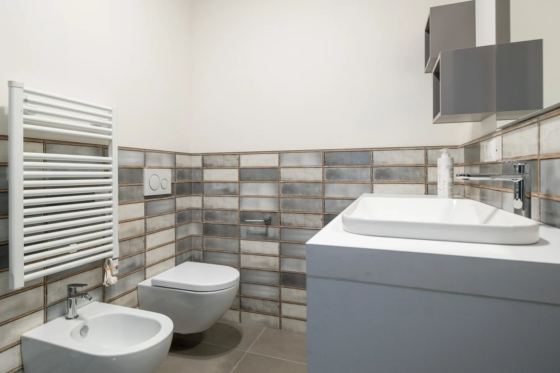Baño con azulejos, lavabo, inodoro y tocador.