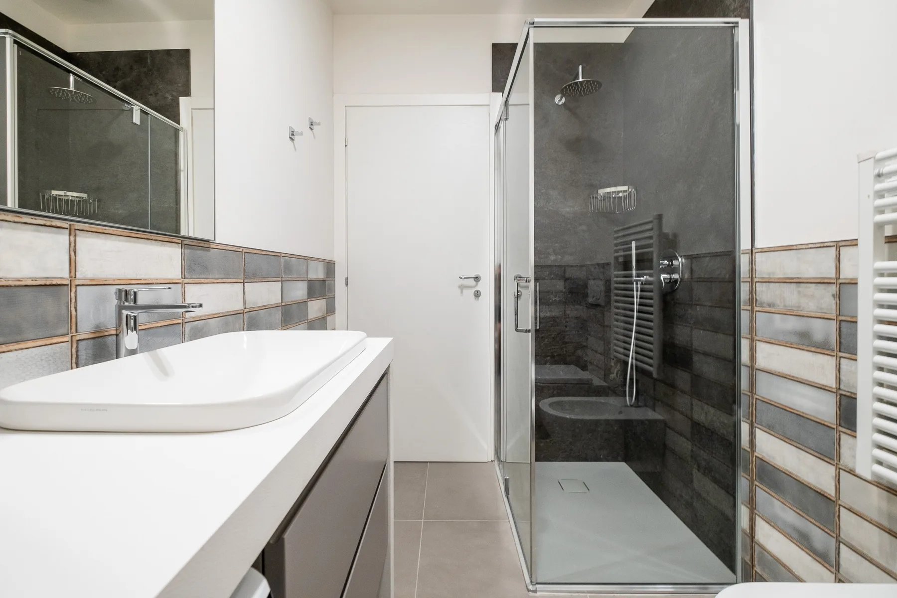 Un baño moderno con una ducha de vidrio y un lavabo blanco.