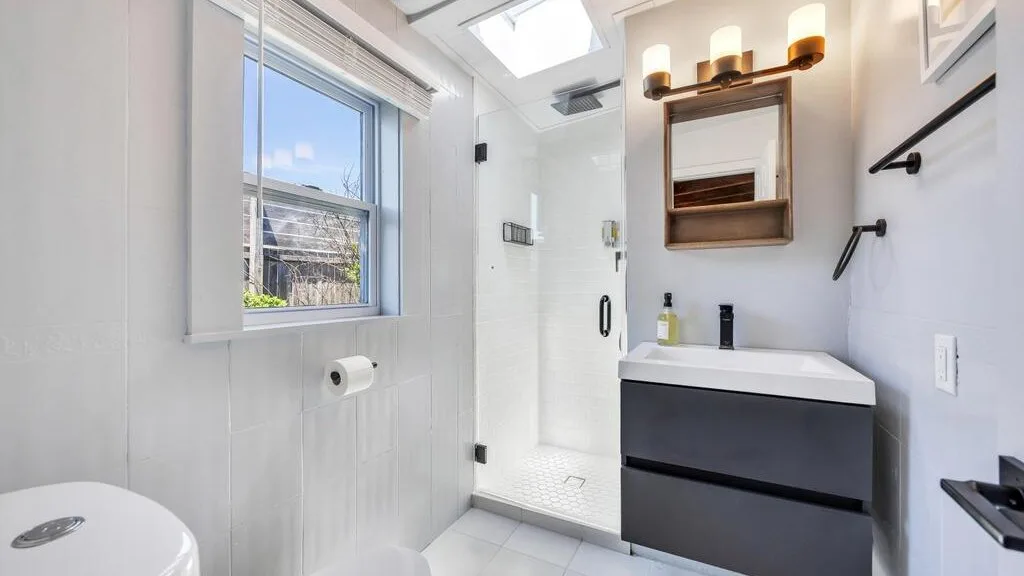 A bright bathroom with a vanity, mirror, and glass shower.