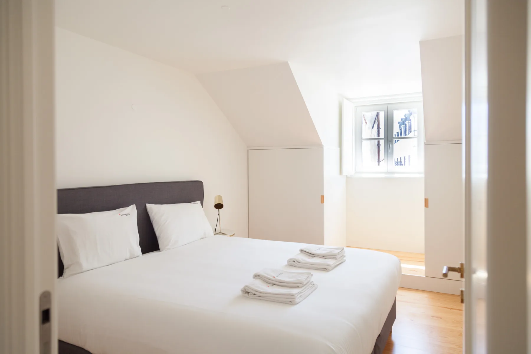 A bedroom with a neatly made bed and a small window.