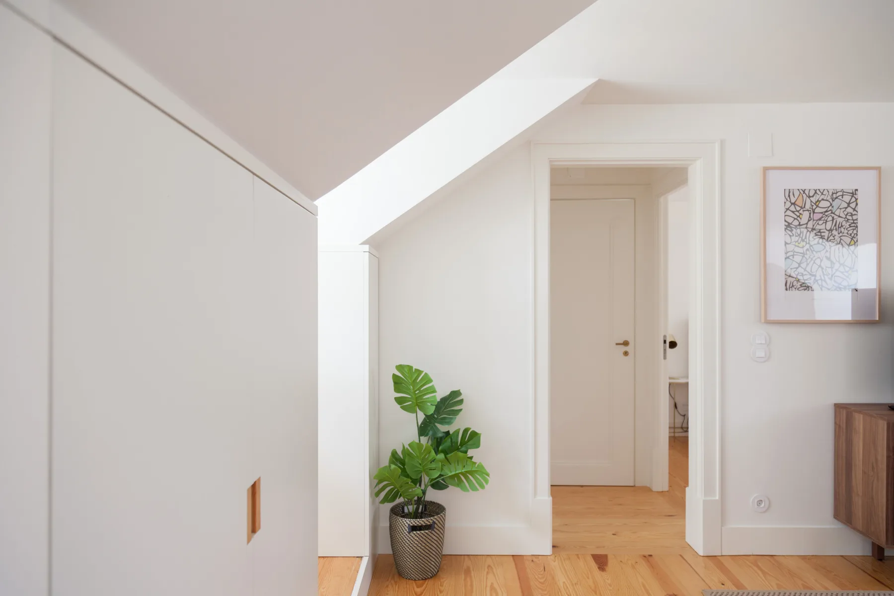 A bright hallway with a closed door and light wood flooring.