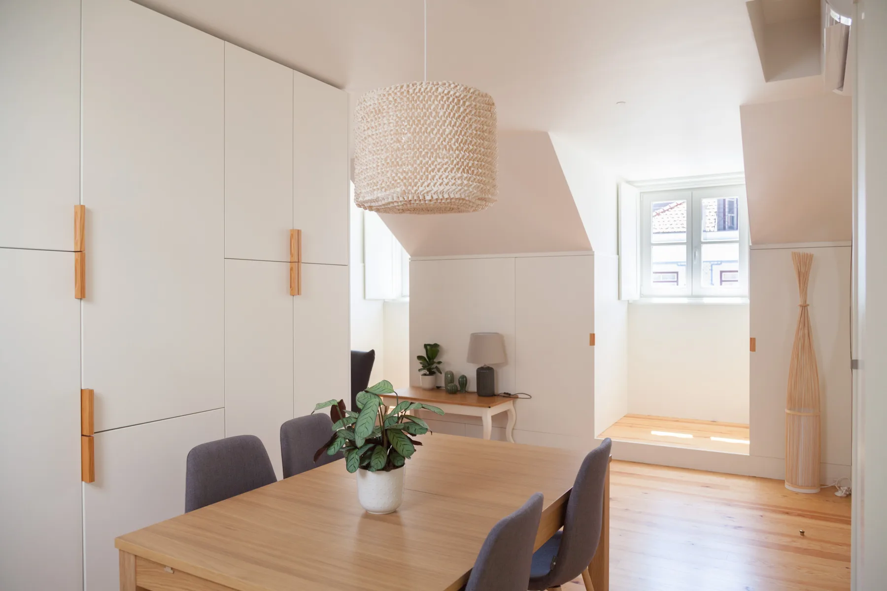 A dining area with a wooden table and chairs beneath a woven pendant light.