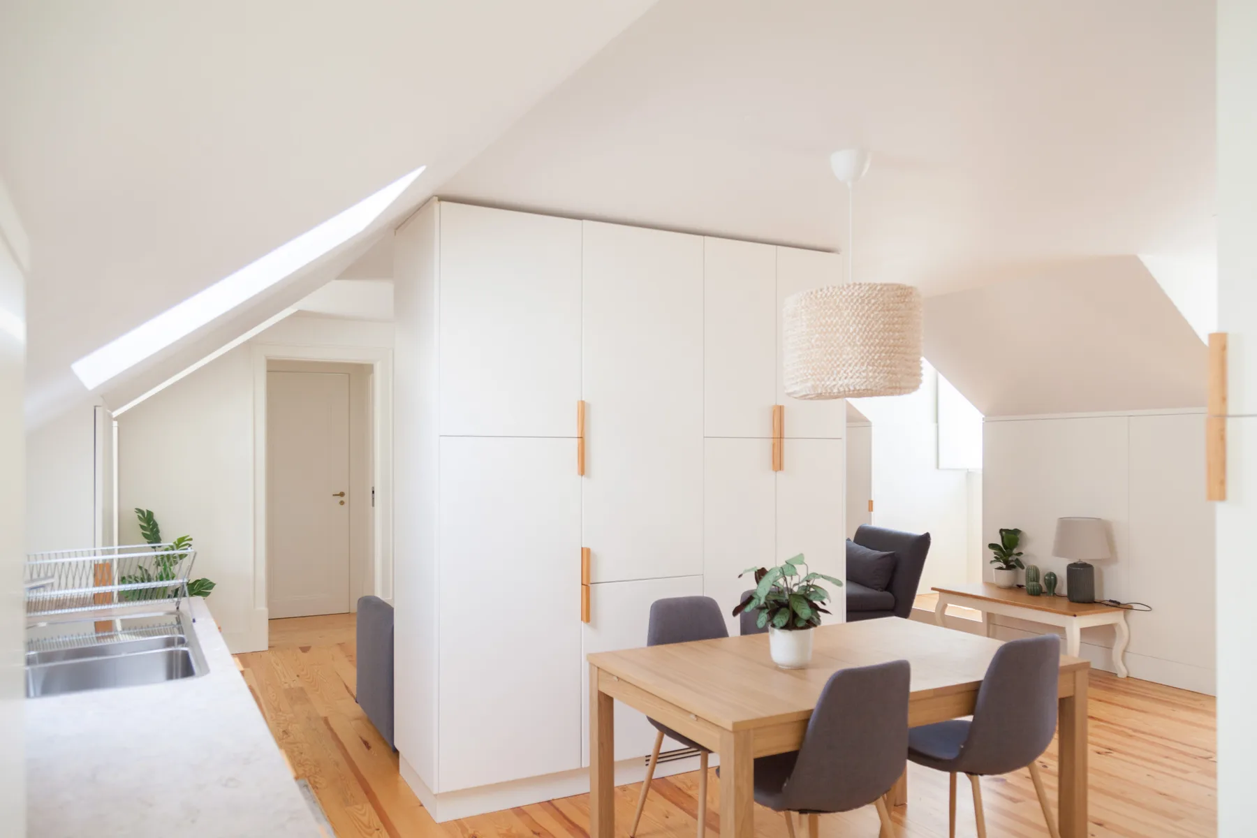 Bright dining area with a wooden table beneath a sloped ceiling.