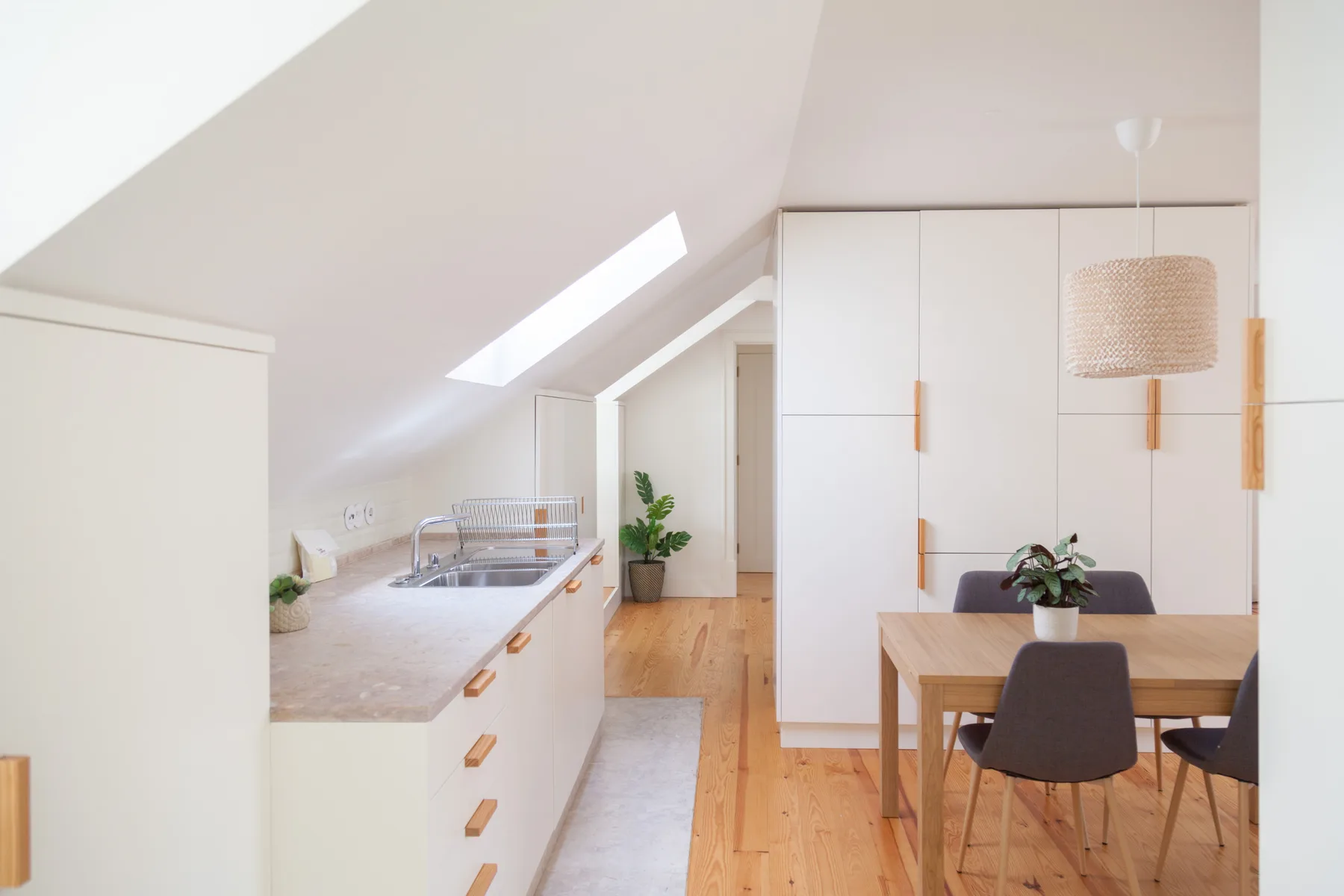 A bright kitchen and dining area with a skylight and wooden table.