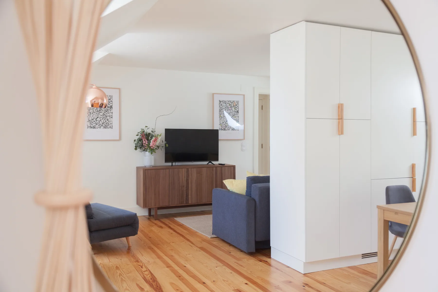 A living room with seating, a television, and wooden flooring.
