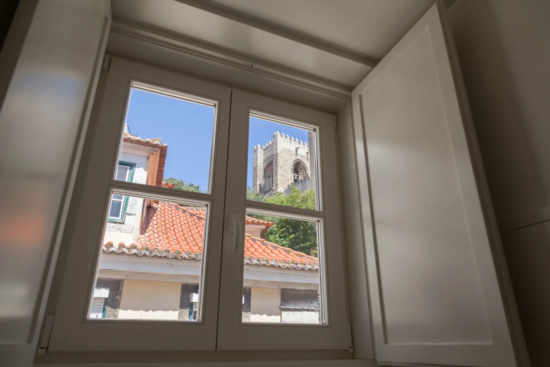 A bright window overlooks red-tiled rooftops and a stone tower.