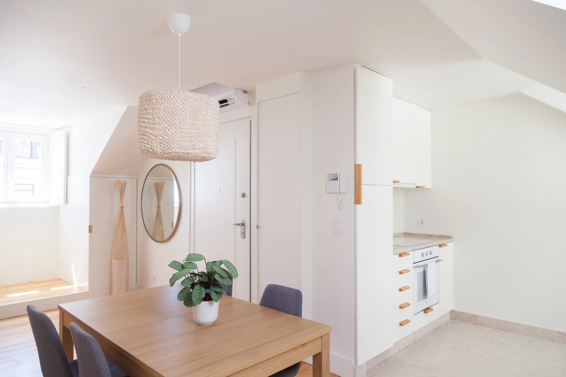 A bright dining area with a wooden table beside a compact kitchen.
