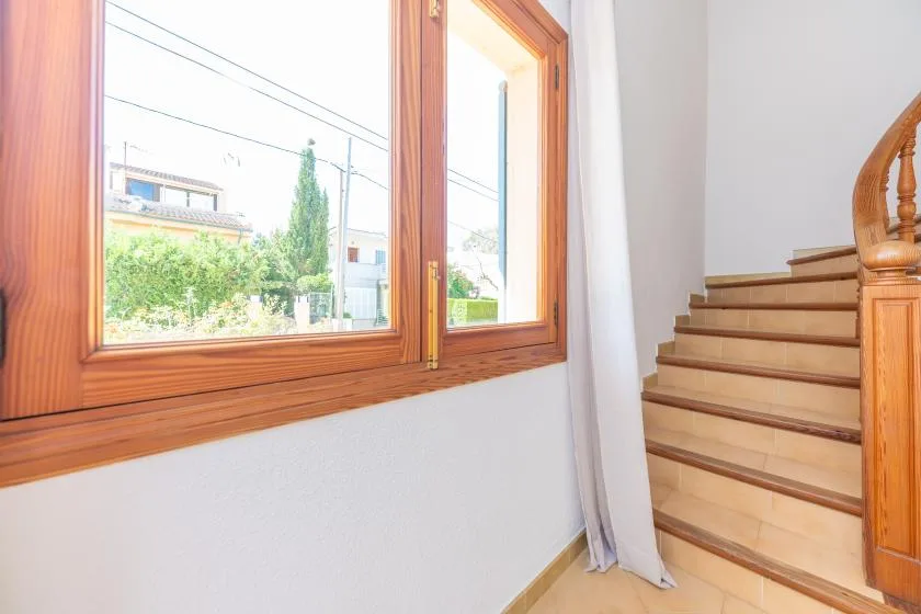 A bright stairway beside a large wooden-framed window.