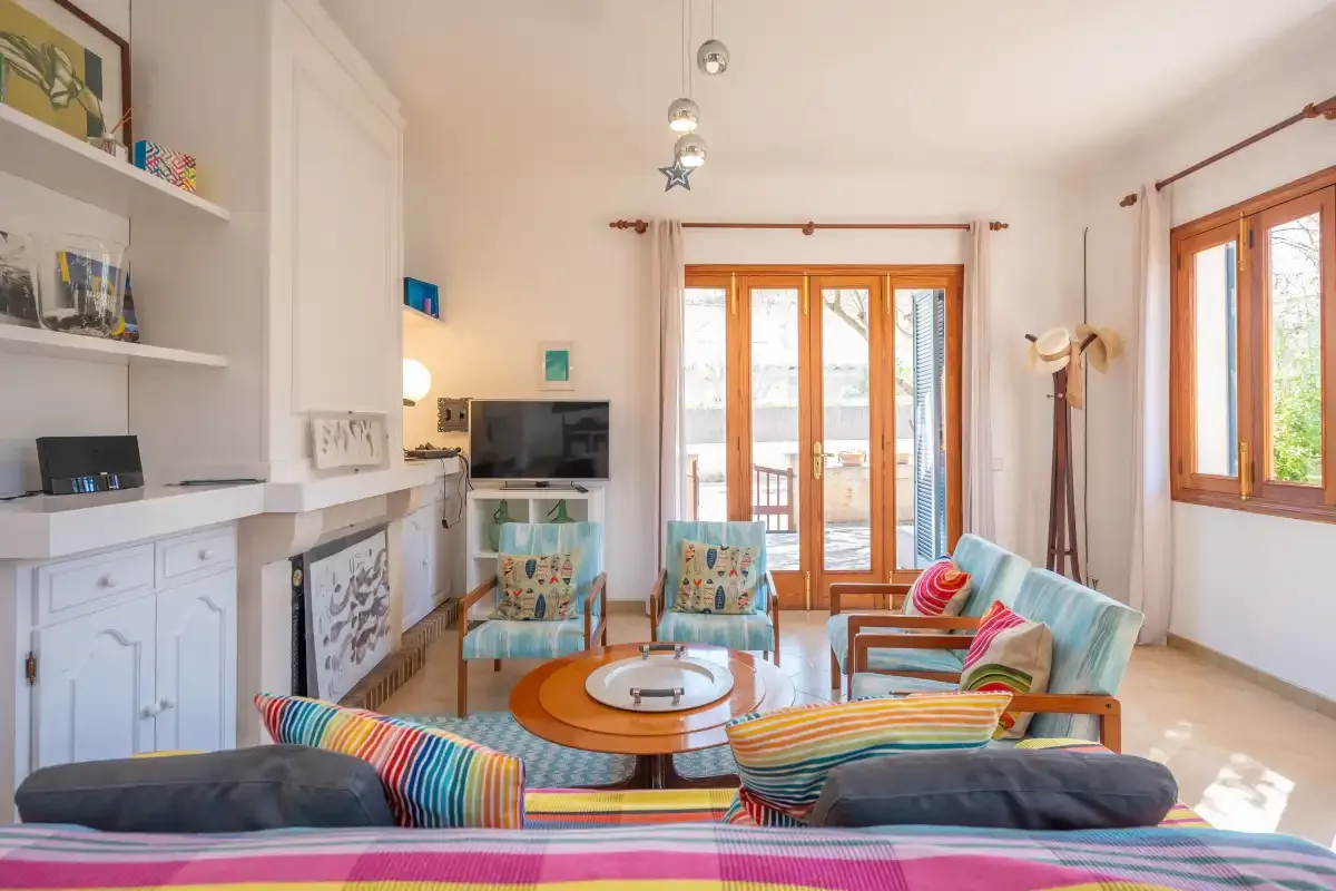A bright living room with colorful seating and glass doors opening to a balcony.