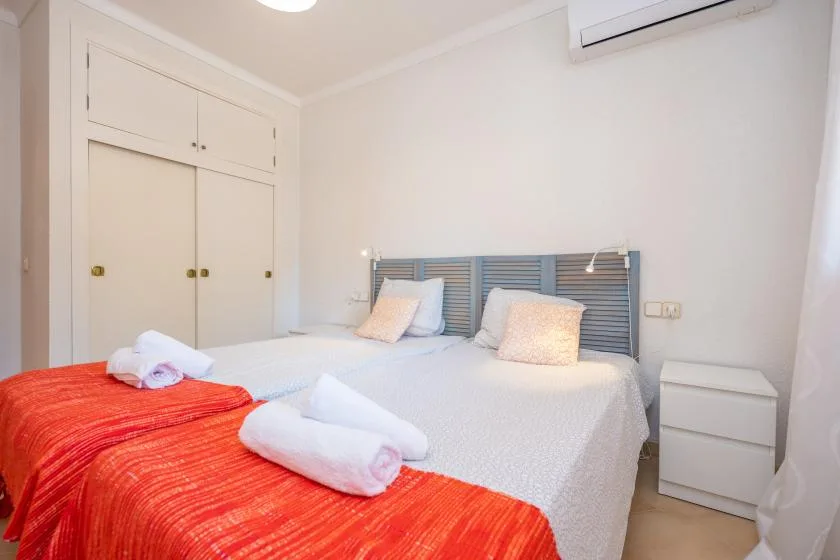 A bedroom with two beds and folded towels on the bedding.