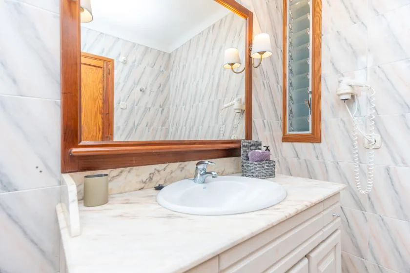 A bathroom vanity with a sink, countertop, and large wall mirror.