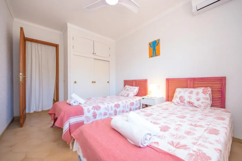 A bedroom with two beds dressed in pink floral bedding.