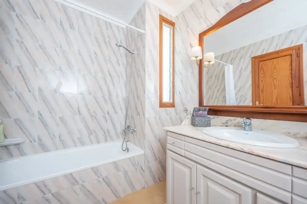 A bathroom with a bathtub, shower fixtures, and a vanity with a mirror.