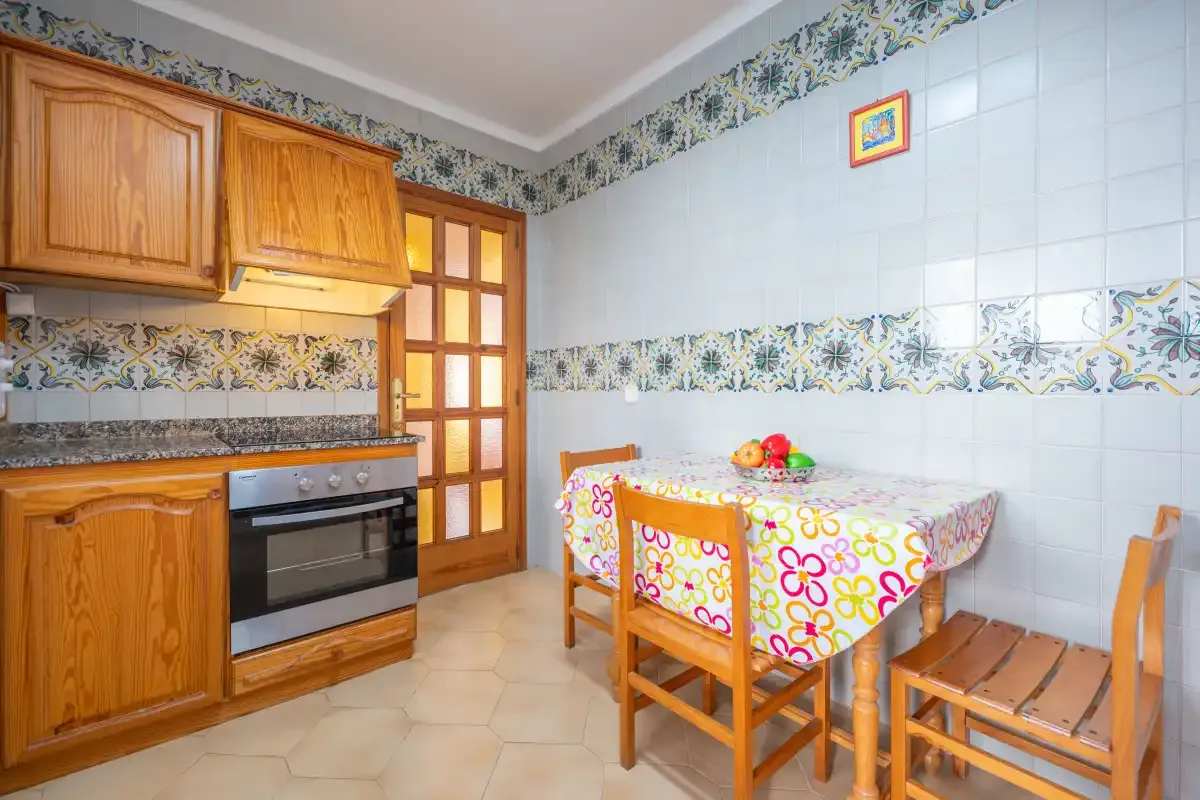 A tiled kitchen and dining area with wooden cabinets and a table.