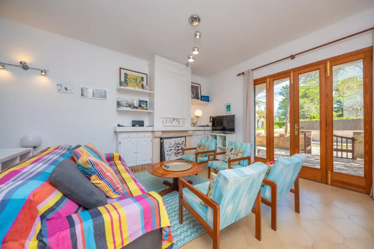 A bright living room with colorful seating and large windows opening onto a patio.